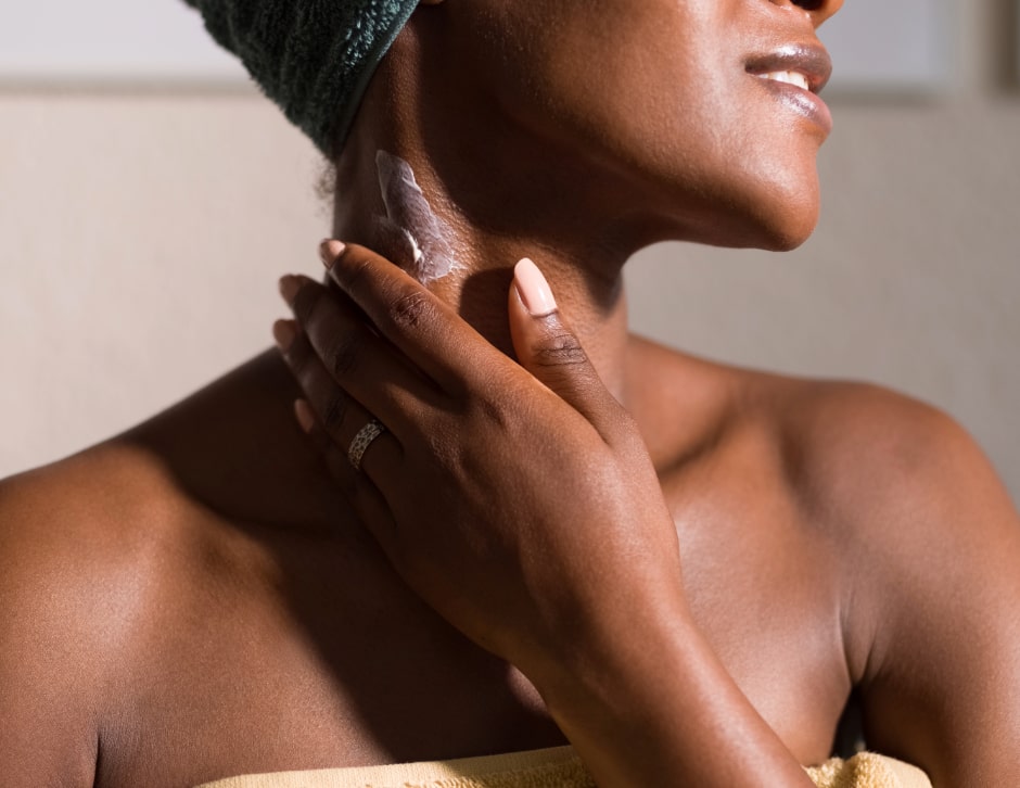 A woman applying skin cream to her neck to prevent dry and aging skin.