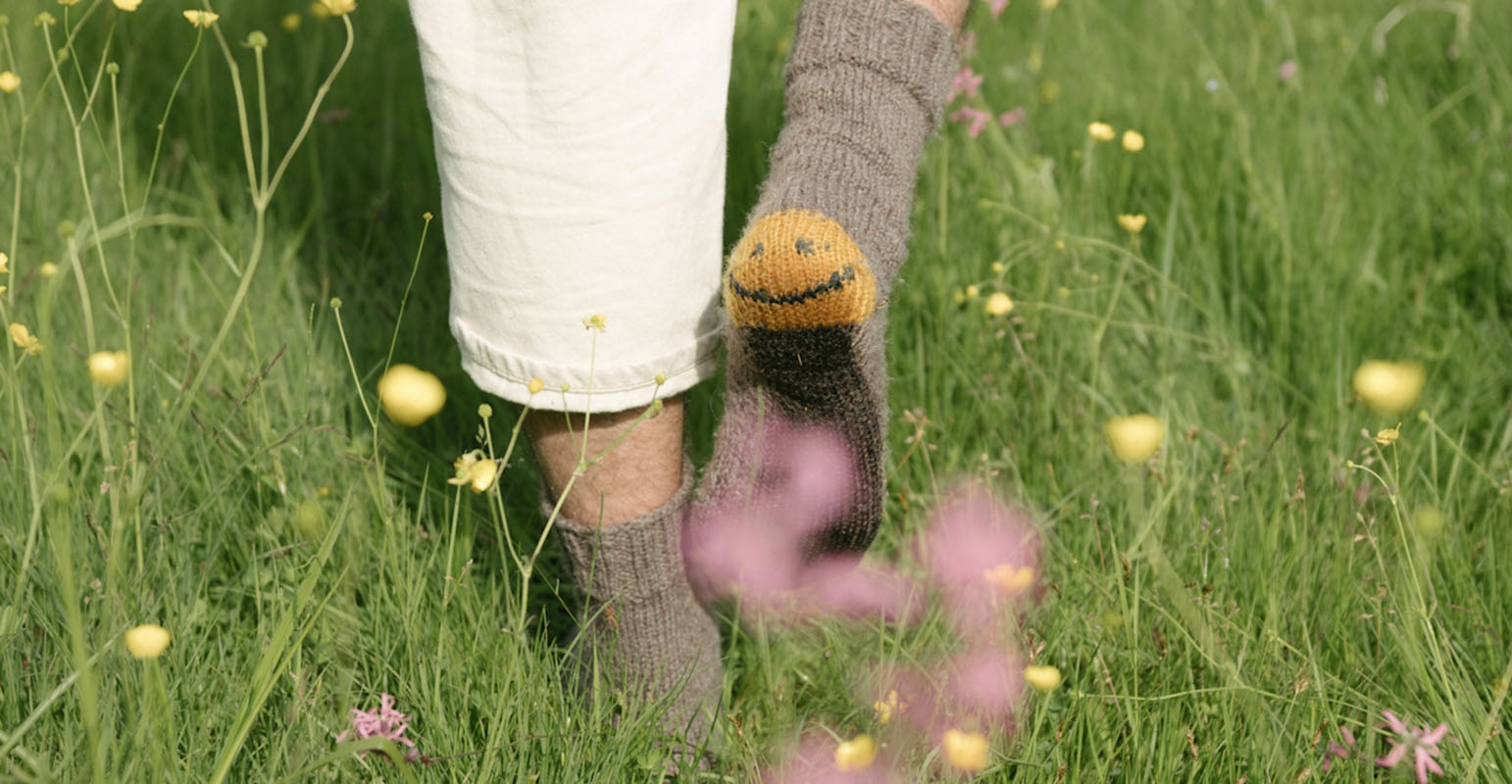 man walking in field with smiley face socks