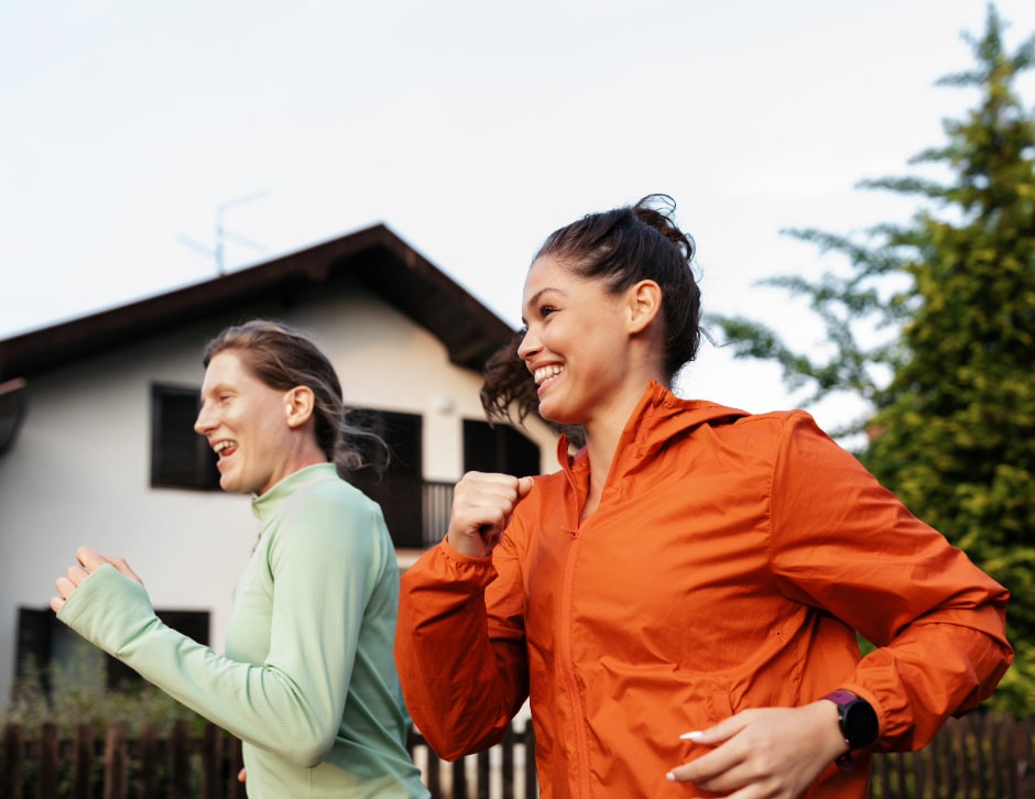 Two women friends running down a residential street.