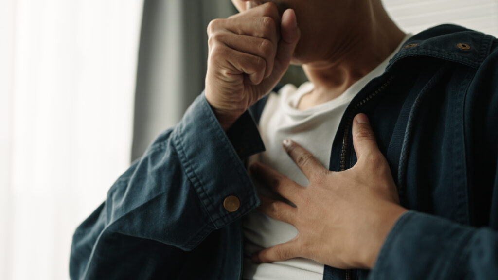 man holding chest and coughing