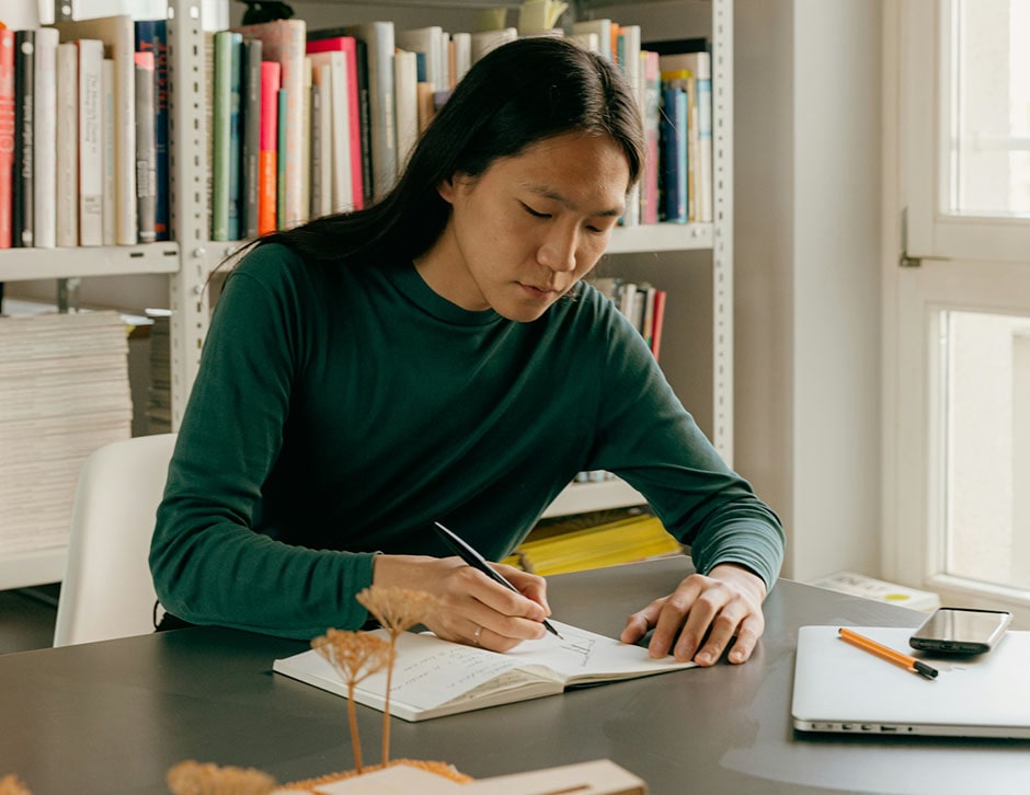 Person sitting at desk writing in notebook