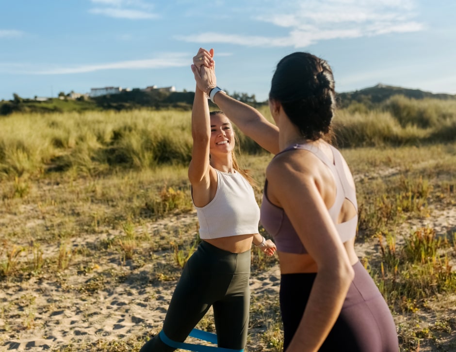 Two women celebrating progress as a trainer congratulates her pupil after a strenuous exercise.