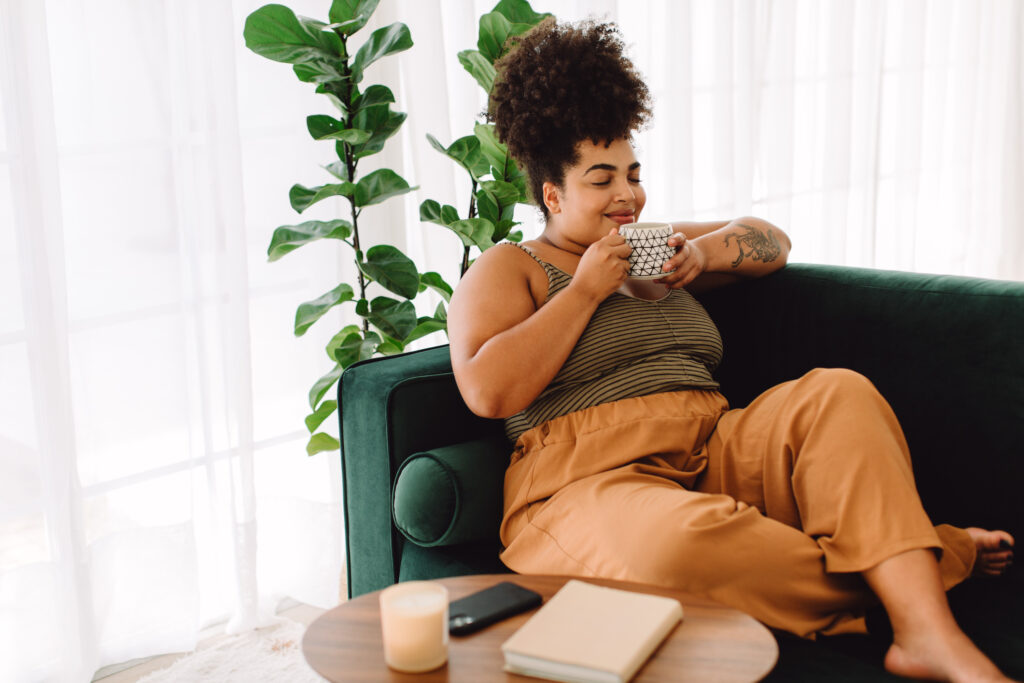 Woman relaxing on sofa and having coffee, enjoying her renewed quality of life after taking semaglutide with minimal side effects.