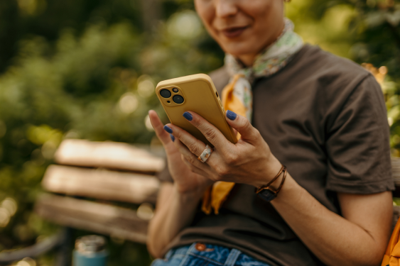woman browsing on phone sitting on beck outside