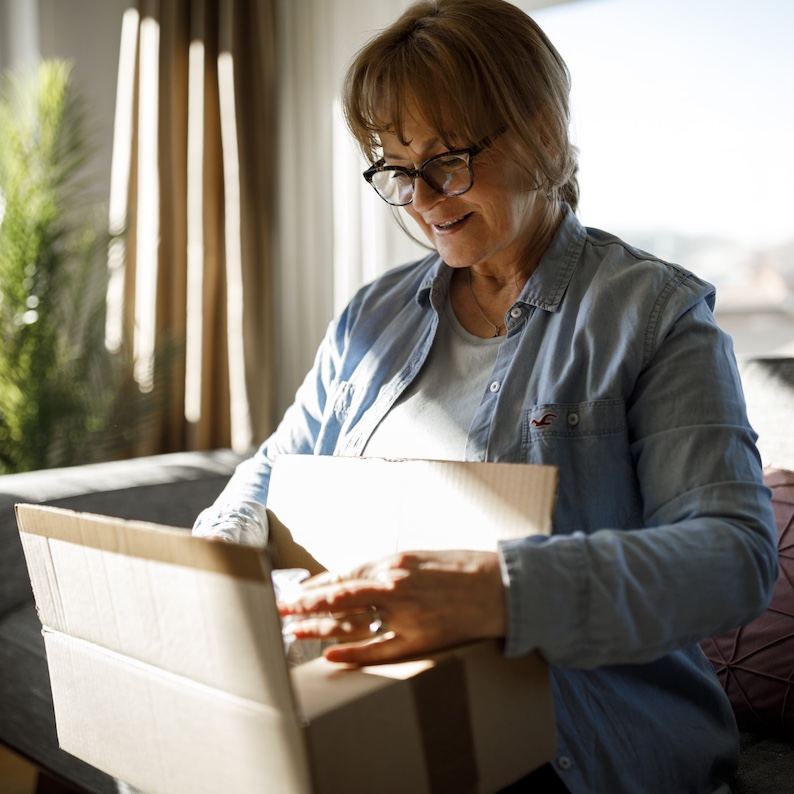 woman at home opening a cardboard package