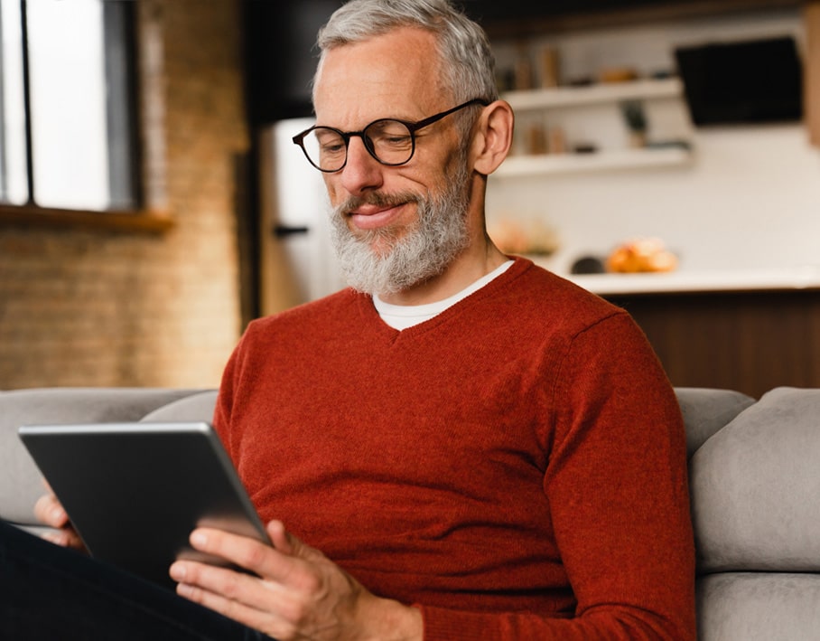 man on his couch at home completing an online visit on his tablet