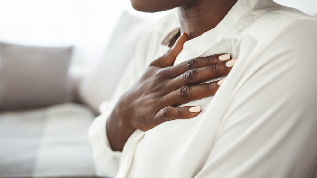 woman holding chest on couch