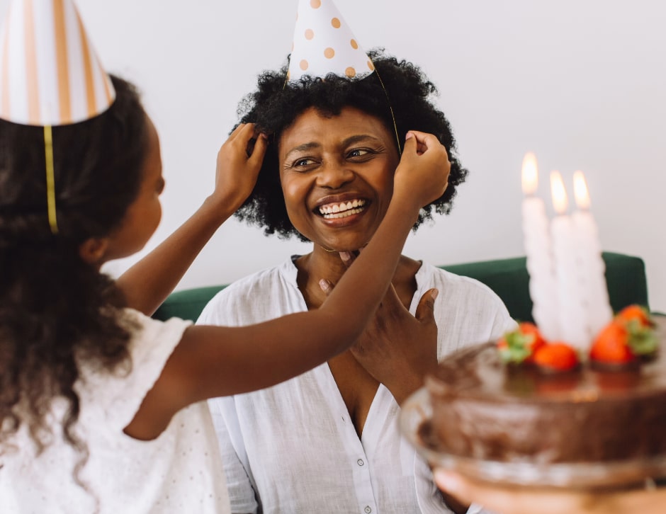 A woman smiling as she enjoys a birthday celebration with her daughter, as if to answer the question "Why do we age?"